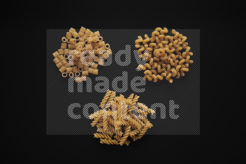 Different pasta types in bunches on black background