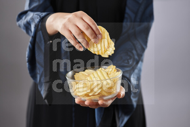 Woman in abaya holding different kinds of snacks in different positions