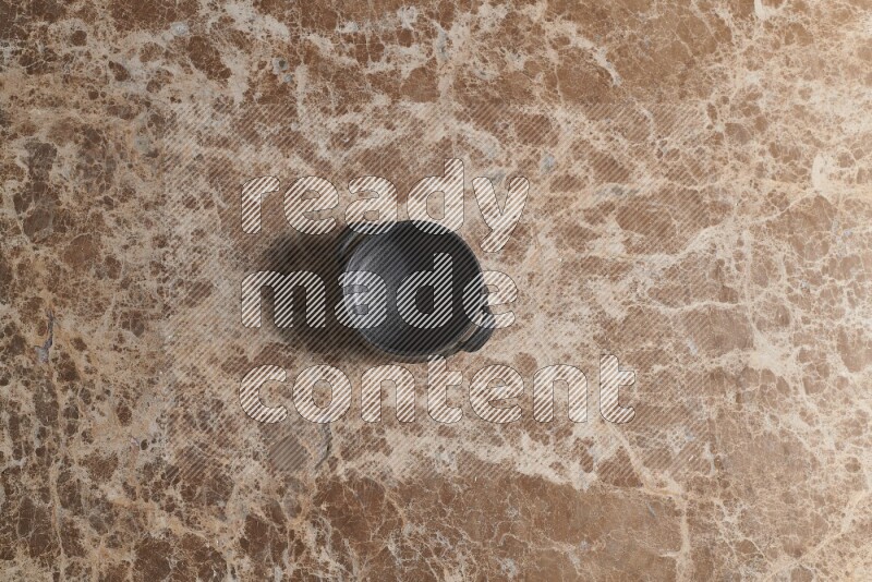 A black pottery bowl on beige marble background