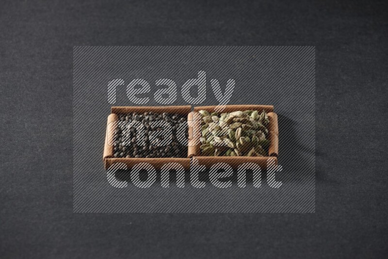 2 squares of cinnamon sticks full of black peppers and cardamom on black flooring