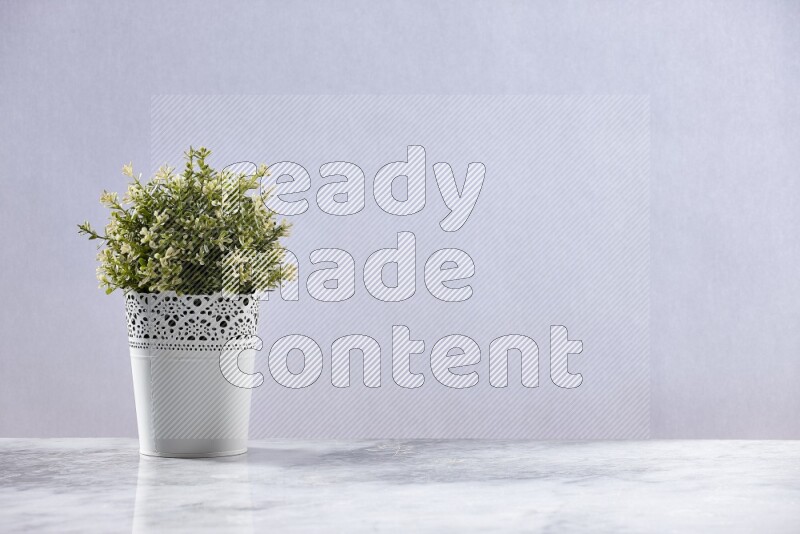 Artificial plant in white decorative pot on grey marble background