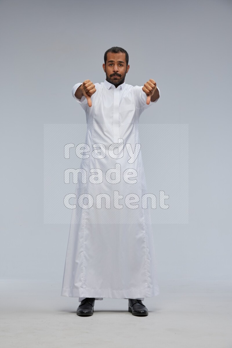 Saudi man Wearing Thob standing interacting with the camera on Gray background
