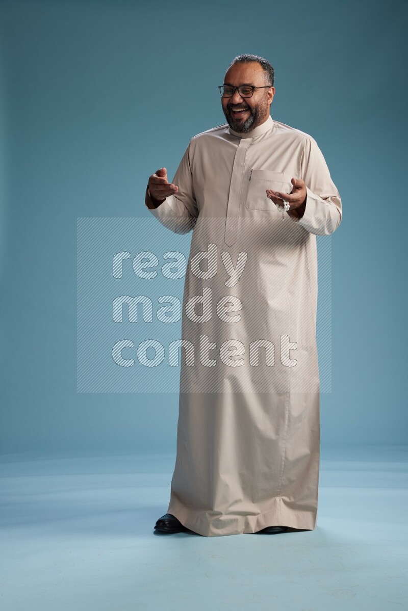 Saudi Man without shimag Standing Interacting with the camera on blue background