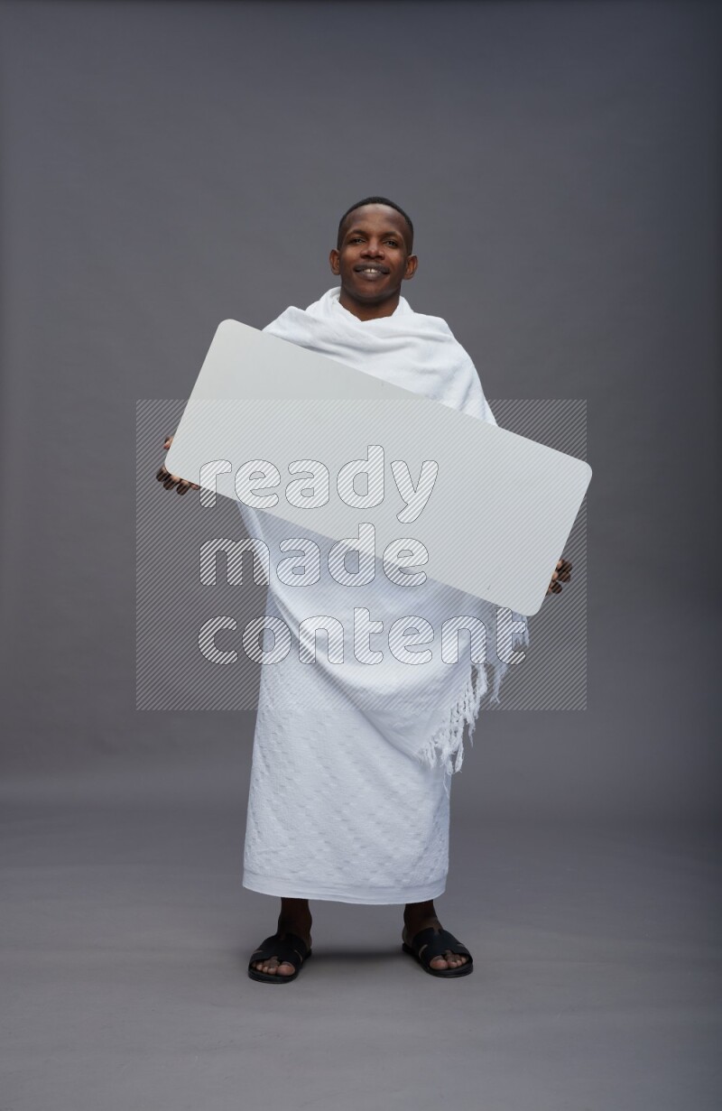 A man wearing Ehram Standing holding board sign on gray background