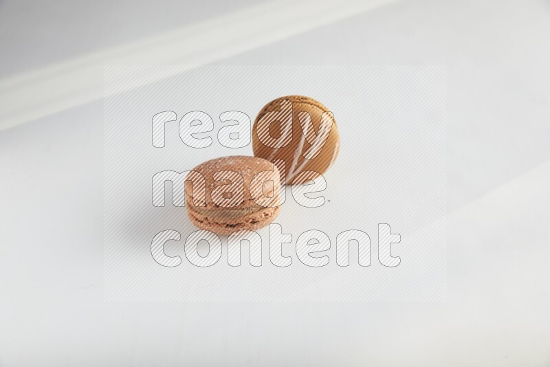 45º Shot of of two assorted Brown Irish Cream, and Brown Hazelnuts macarons on white background