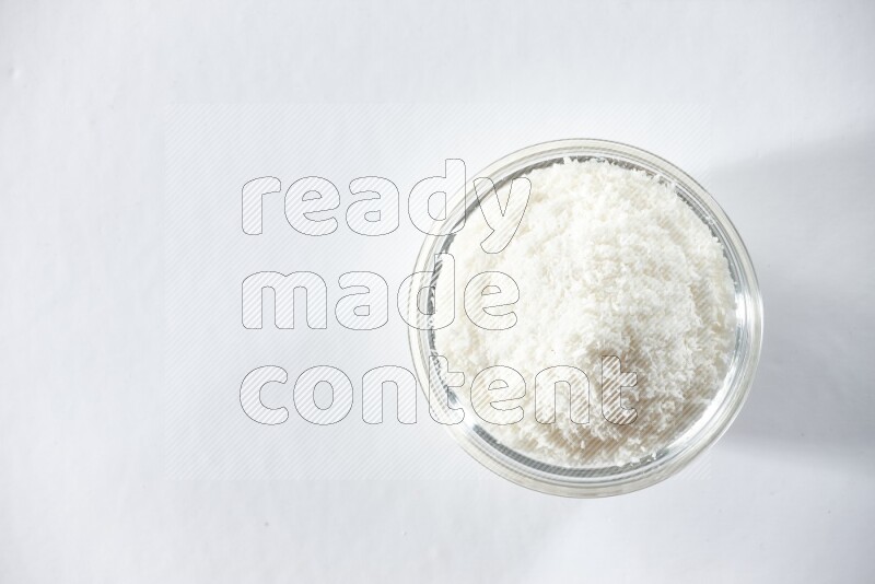 A glass bowl full of desiccated coconut on a white background in different angles