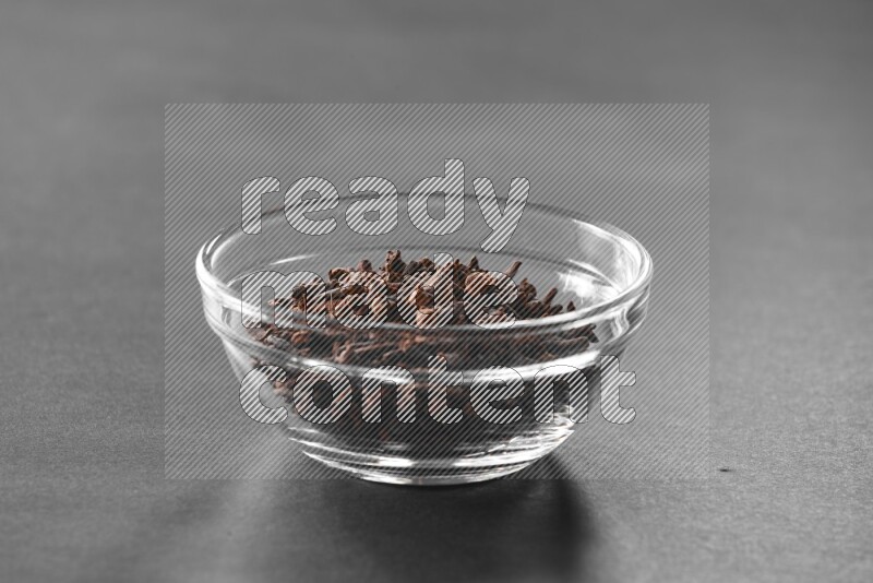 A glass bowl full of cloves on black flooring