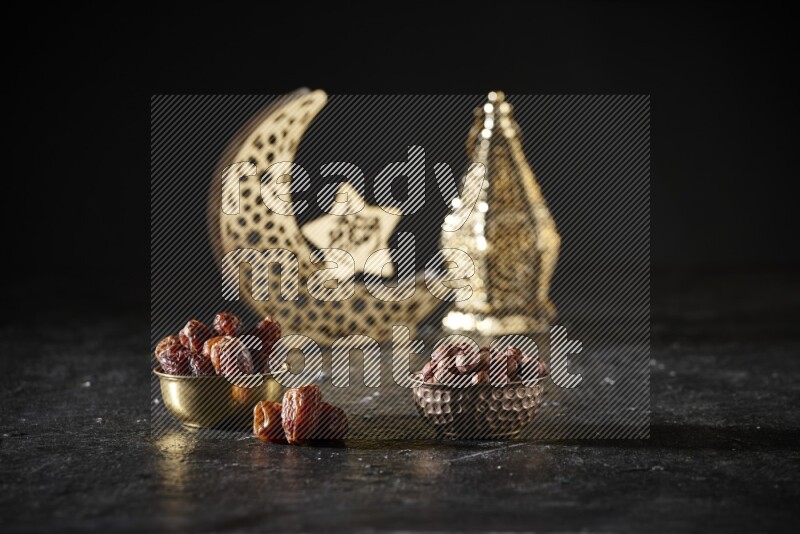 Dates in a metal bowl with hazelnuts beside golden lanterns in a dark setup