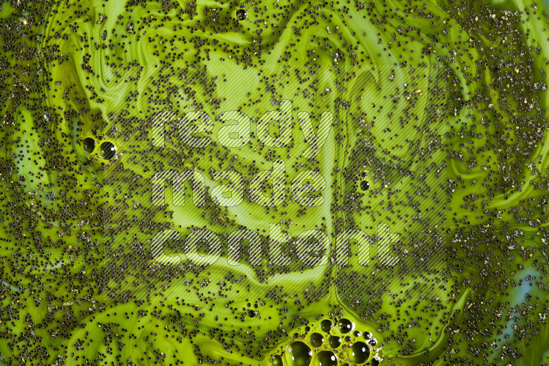 A close-up of sparkling gold glitter scattered on swirling green background