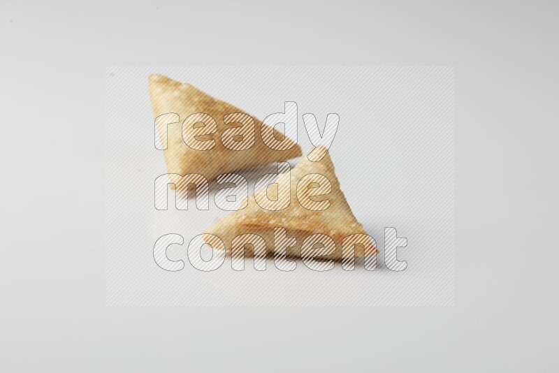 Two fried sambosas on a white background