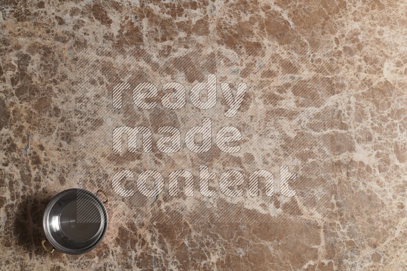 A small copper pot on beige marble background