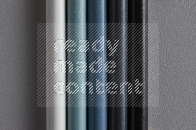 A collection of colored pencils arranged showcasing a gradient of white, grey and black hues on grey background