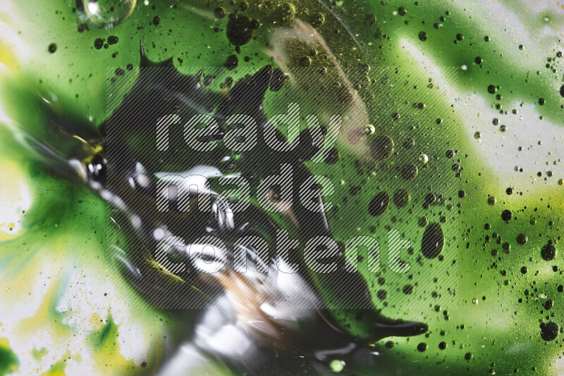 لقطات مقربة لقطرات ألوان مائية خضراء وصفراء على سطح الزيت على خلفية بيضاء