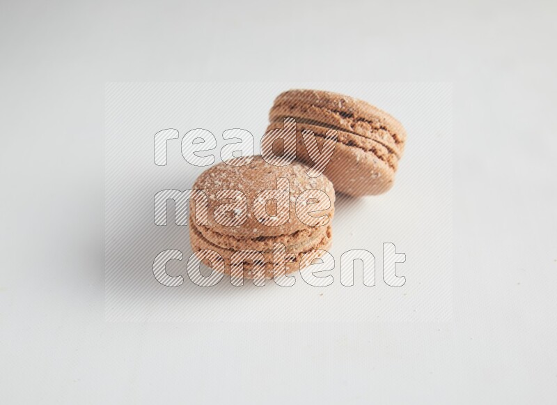 45º Shot of two Brown Hazelnuts macarons on white background