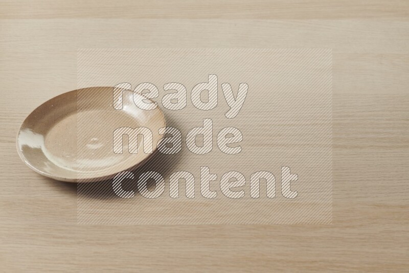 A beige pottery plate on light wooden background
