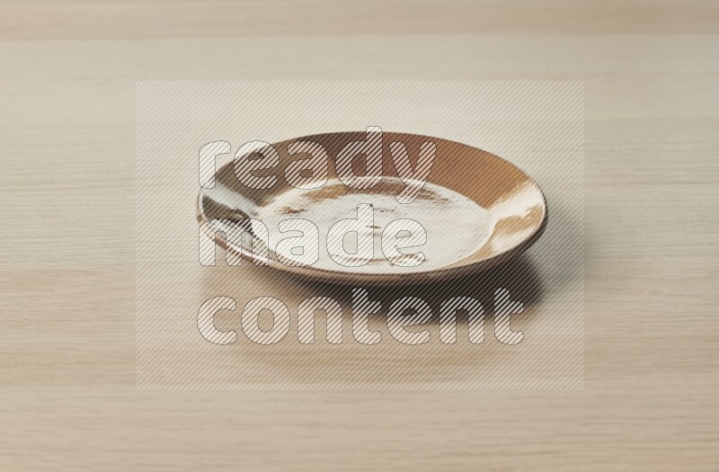 A multicolored pottery plate on light wooden background