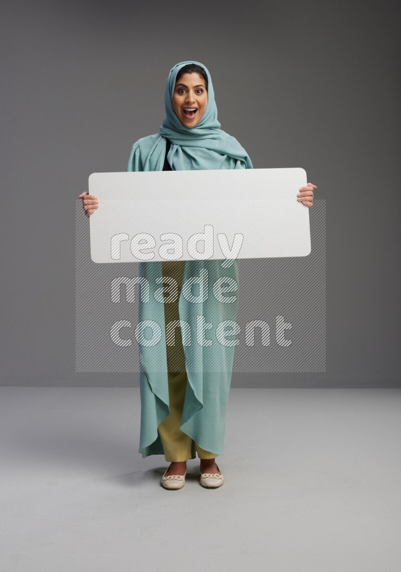 Saudi Woman wearing Abaya standing holding board on Gray background