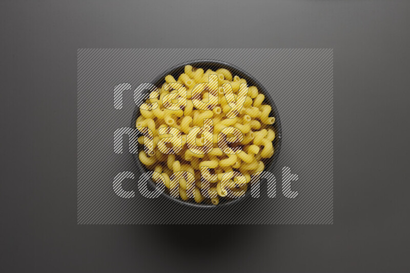 Twist pasta in a pottery bowl on grey background