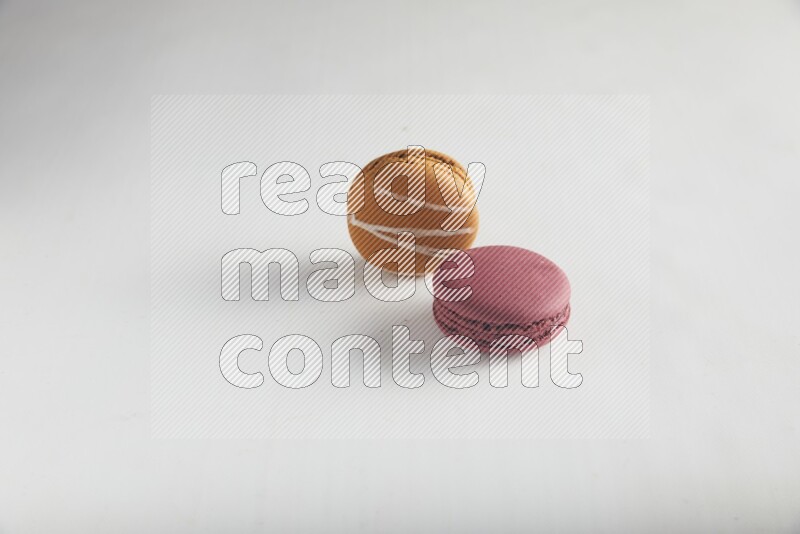 45º Shot of of two assorted Brown Irish Cream, and Red Cherry macarons on white background