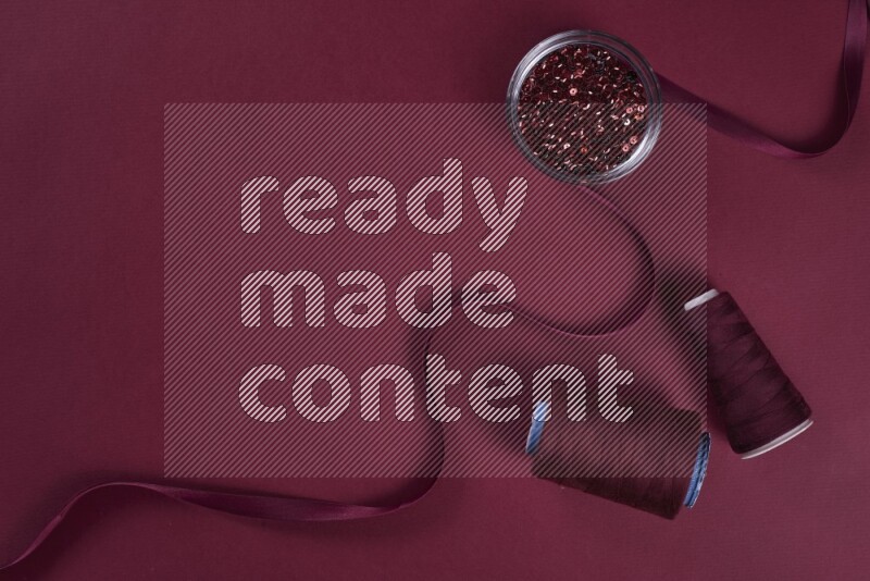 مجموعة من أدوات الخياطة والتفصيل حمراء اللون على خلفية حمراء