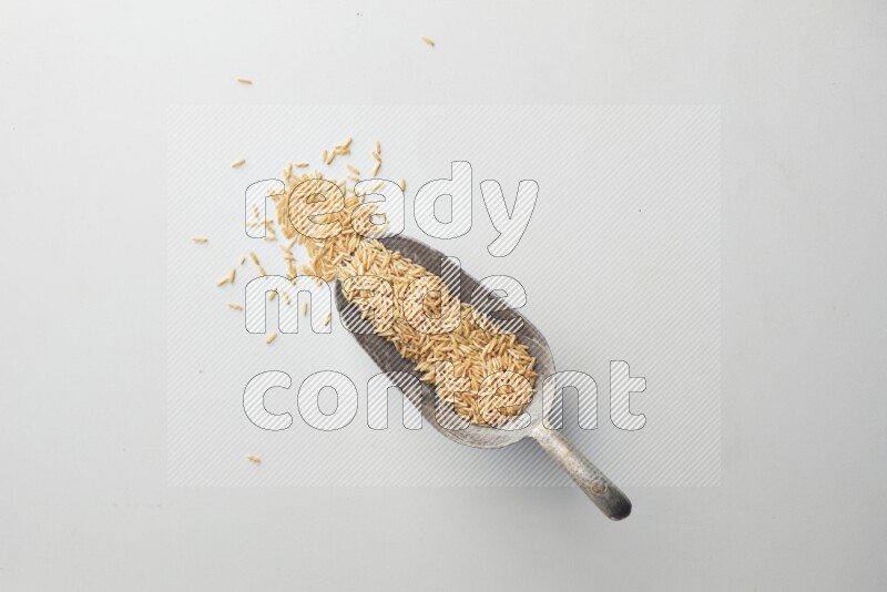Top-view of a long grain brown rice, and shovel on white background