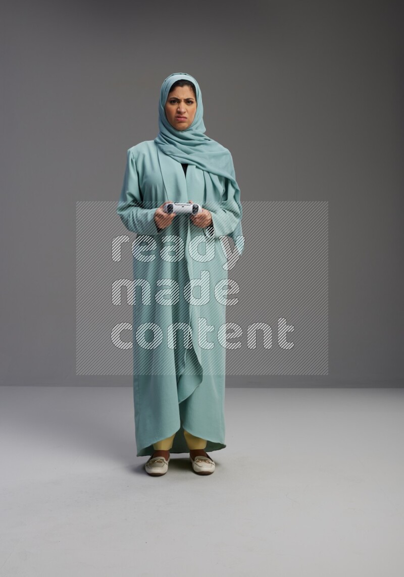 Saudi Woman wearing Abaya standing Playing Games on Gray background
