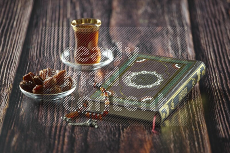 Quran with dates, prayer beads and different drinks all placed on wooden background