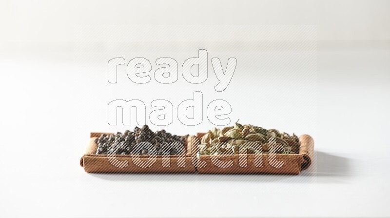 2 squares of cinnamon sticks full of cardamom and black pepper on white flooring