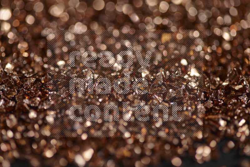 Bronze shimmering fragments of glass scattered on a black background