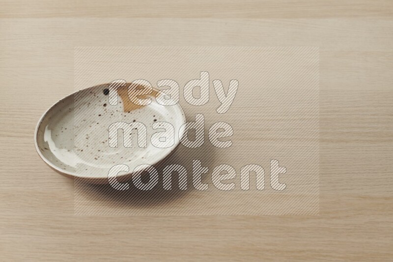 A multicolored pottery plate on light wooden background