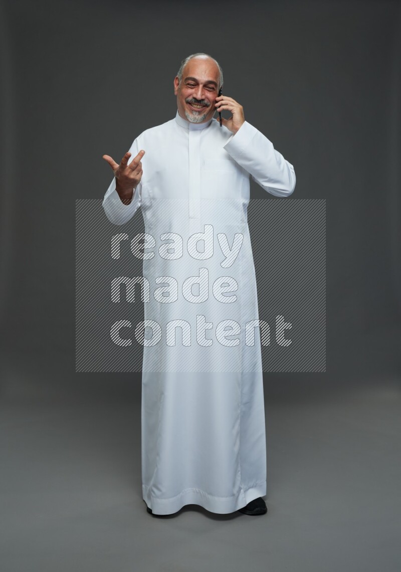 Saudi man without shomag Standing talking on phone on gray background