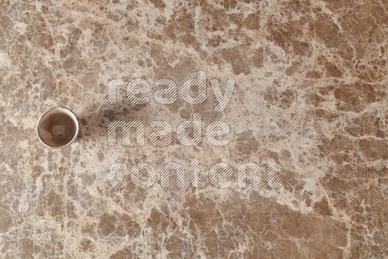 A pottery cup on beige marble background