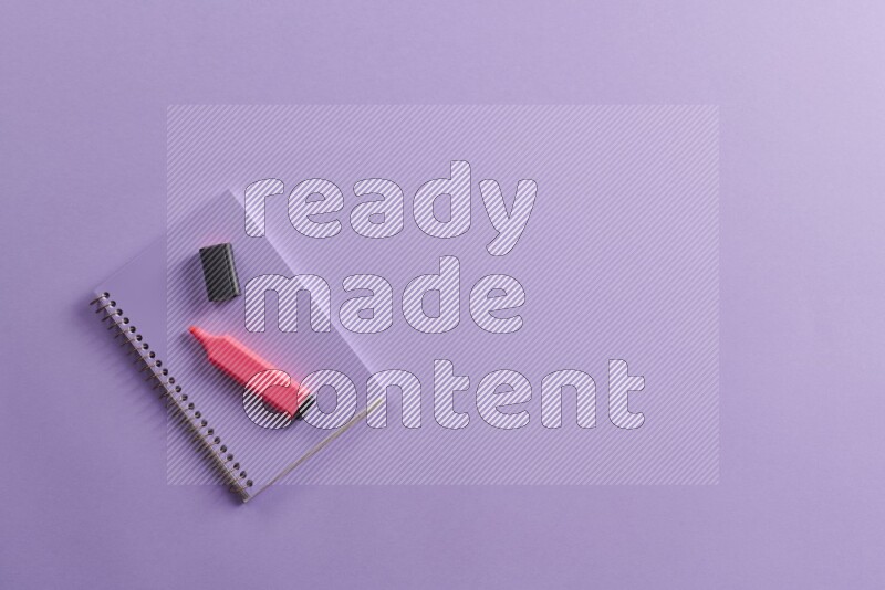 A purple notebook with different school supplies on purple background