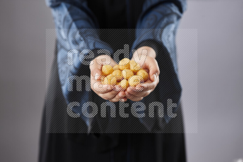 Woman in abaya holding different kinds of snacks in different positions
