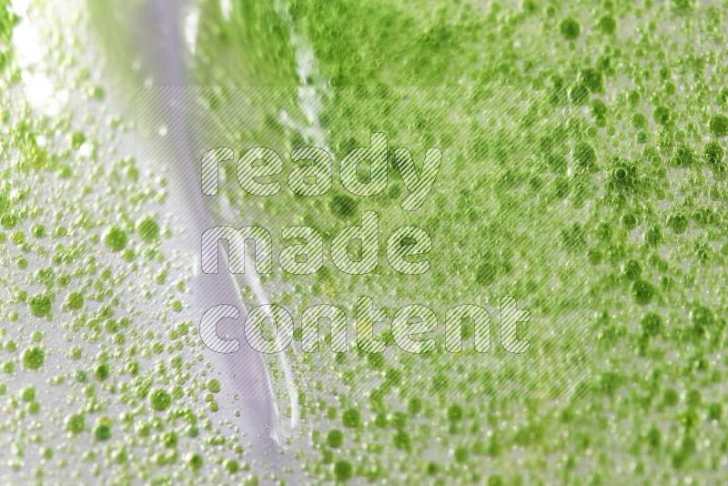 Close-ups of abstract green watercolor drops on oil Surface on white background