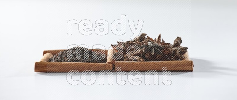 مربعان من أعواد القرفة ممتلئان بالشاي الأسود واليانسون النجمي علي خلفية بيضاء