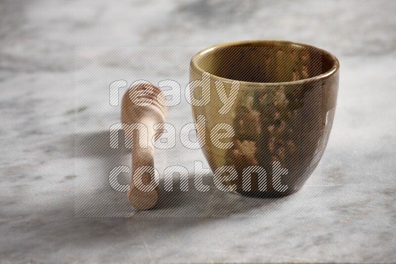 Multicolored pottery cup with wooden honey dipper on the side on grey marble background