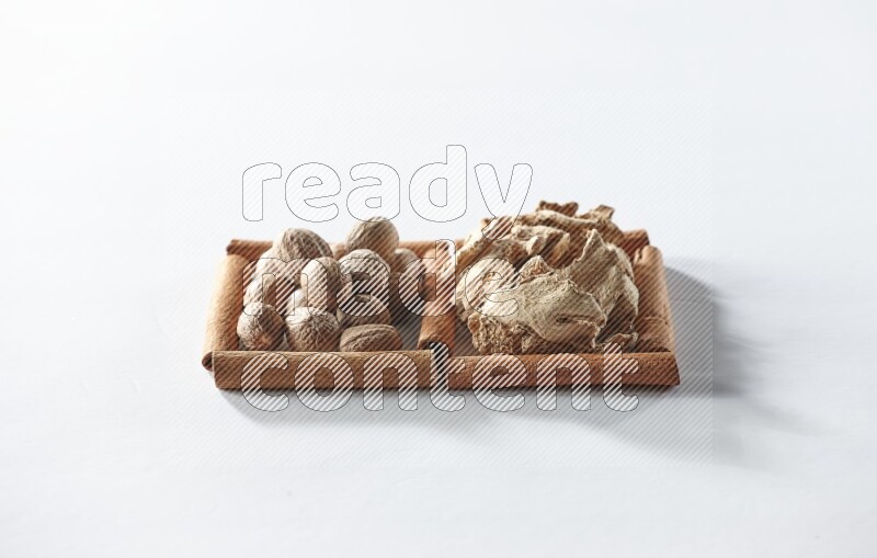 مربعان من أعواد القرفة ممتلئان بالزنجبيل المجفف وجوزة الطيب علي خلفية بيضاء