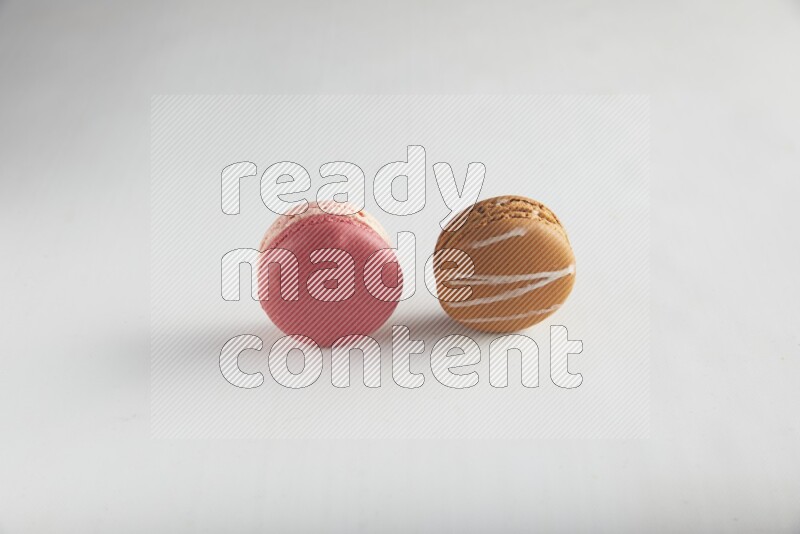 45º Shot of of two assorted Brown Irish Cream, and Pink Litchi Raspberry macarons on white background