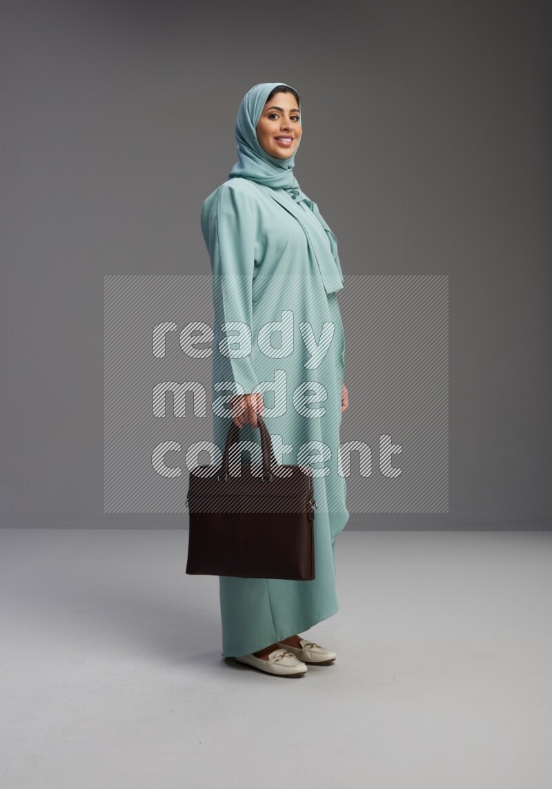Saudi Woman wearing Abaya standing holding bag on Gray background