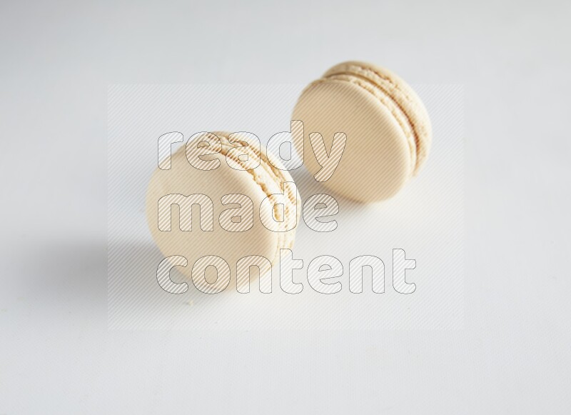 45º Shot of two White Caramel fleur de sel macarons on white background