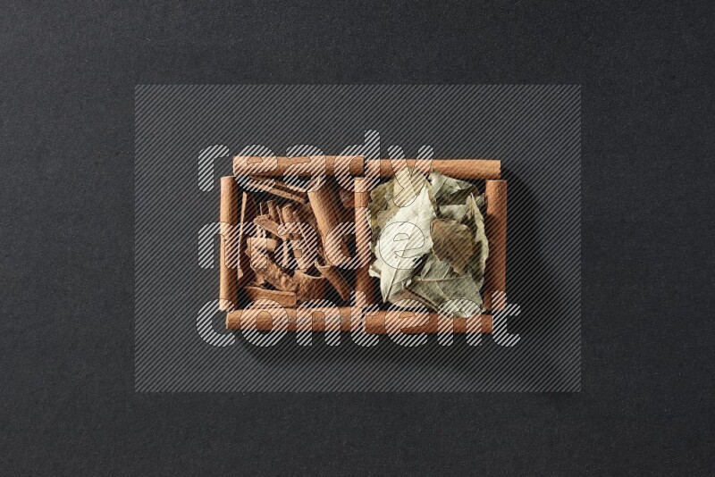 2 squares of cinnamon sticks full of cinnamon and bay laurel leaves on black flooring