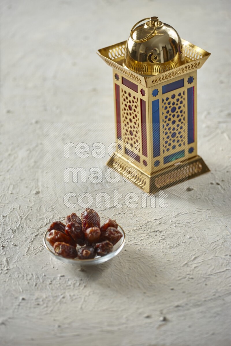 A golden lantern with different drinks, dates, nuts, prayer beads and quran on textured white background