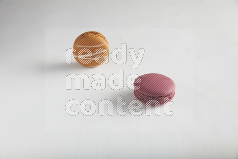 45º Shot of of two assorted Brown Irish Cream, and Red Cherry macarons on white background