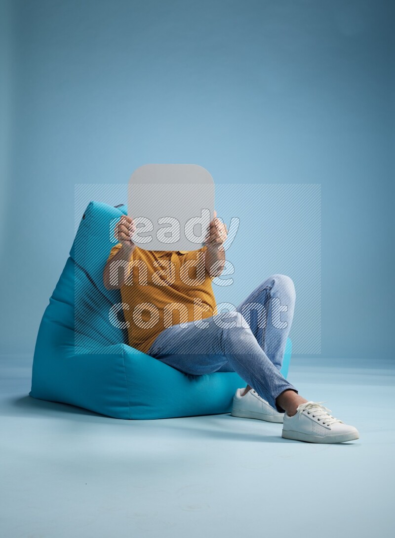 A man sitting on a blue beanbag and holding social media sign