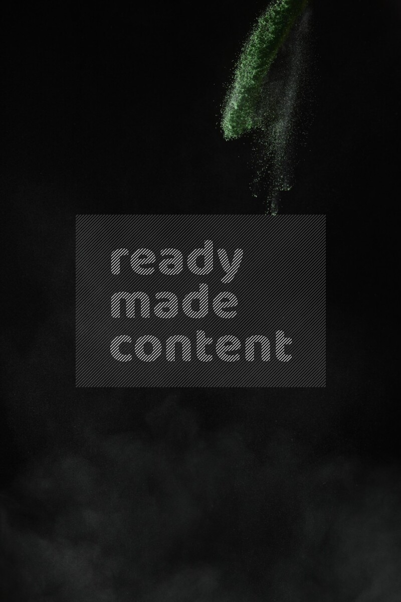 A side view of green powder explosion on black background