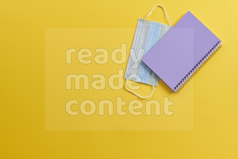 A purple notebook with different school supplies on yellow background