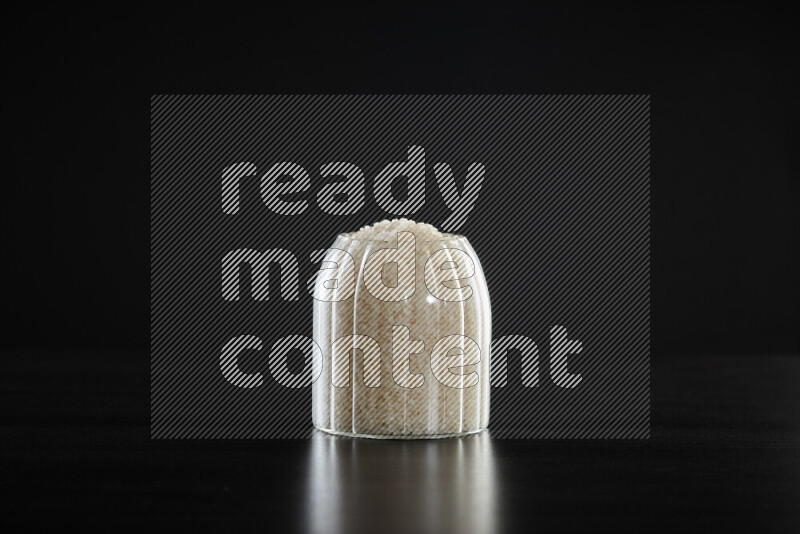 White rice in a glass jar on black background