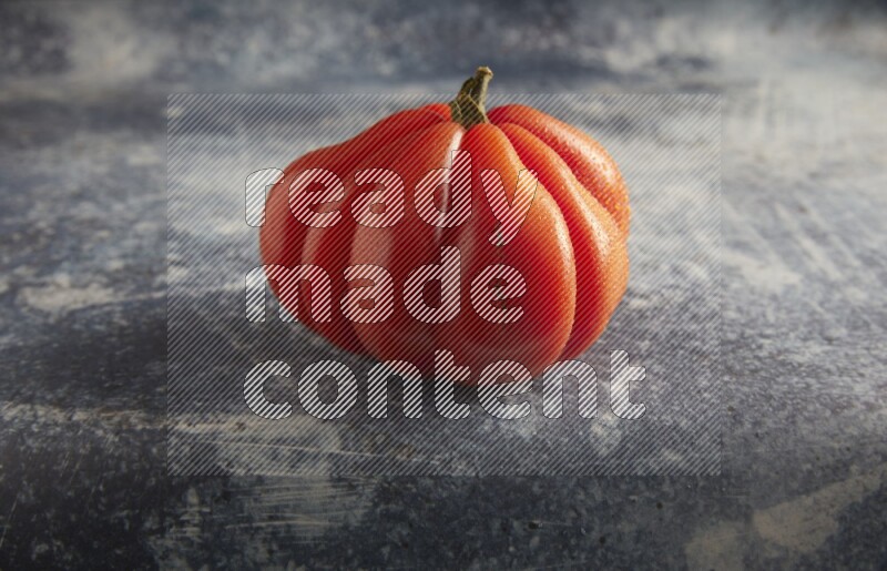 45 degree single heirloom tomato on a textured rustic blue background