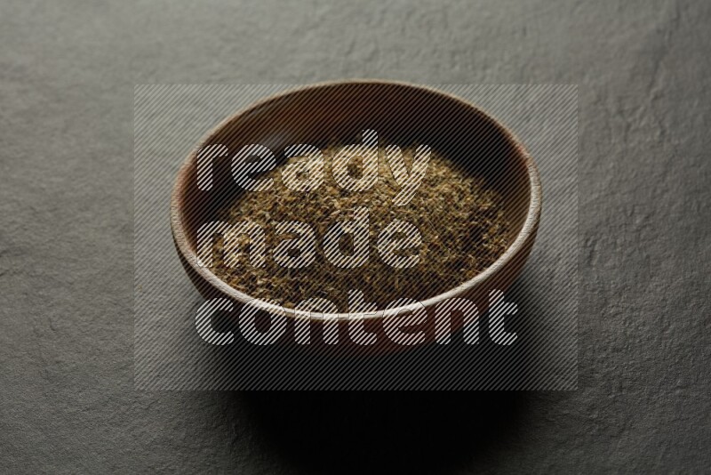 wooden round sauce bowl filled with herbs on grey textured countertop